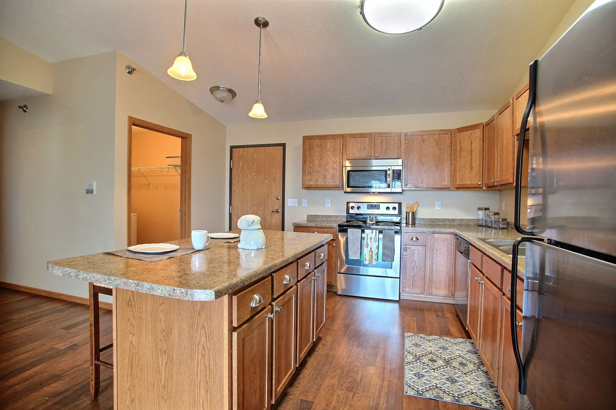a kitchen with stainless steel appliances and wooden cabinets. Fargo, ND Wolf Creek Apartments