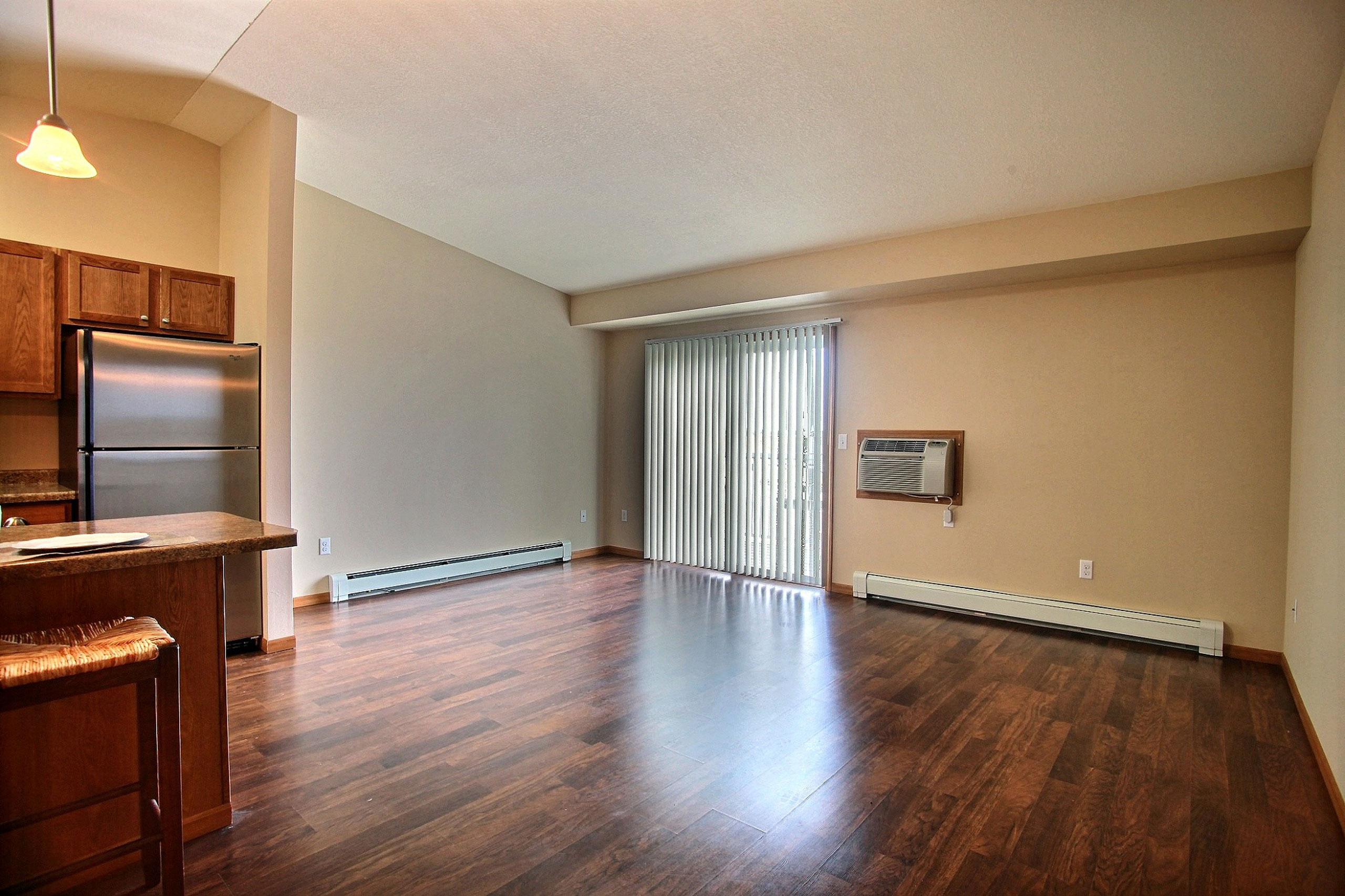 a living room with a glass sliding door and wood floors. Fargo, ND Wolf Creek Apartments