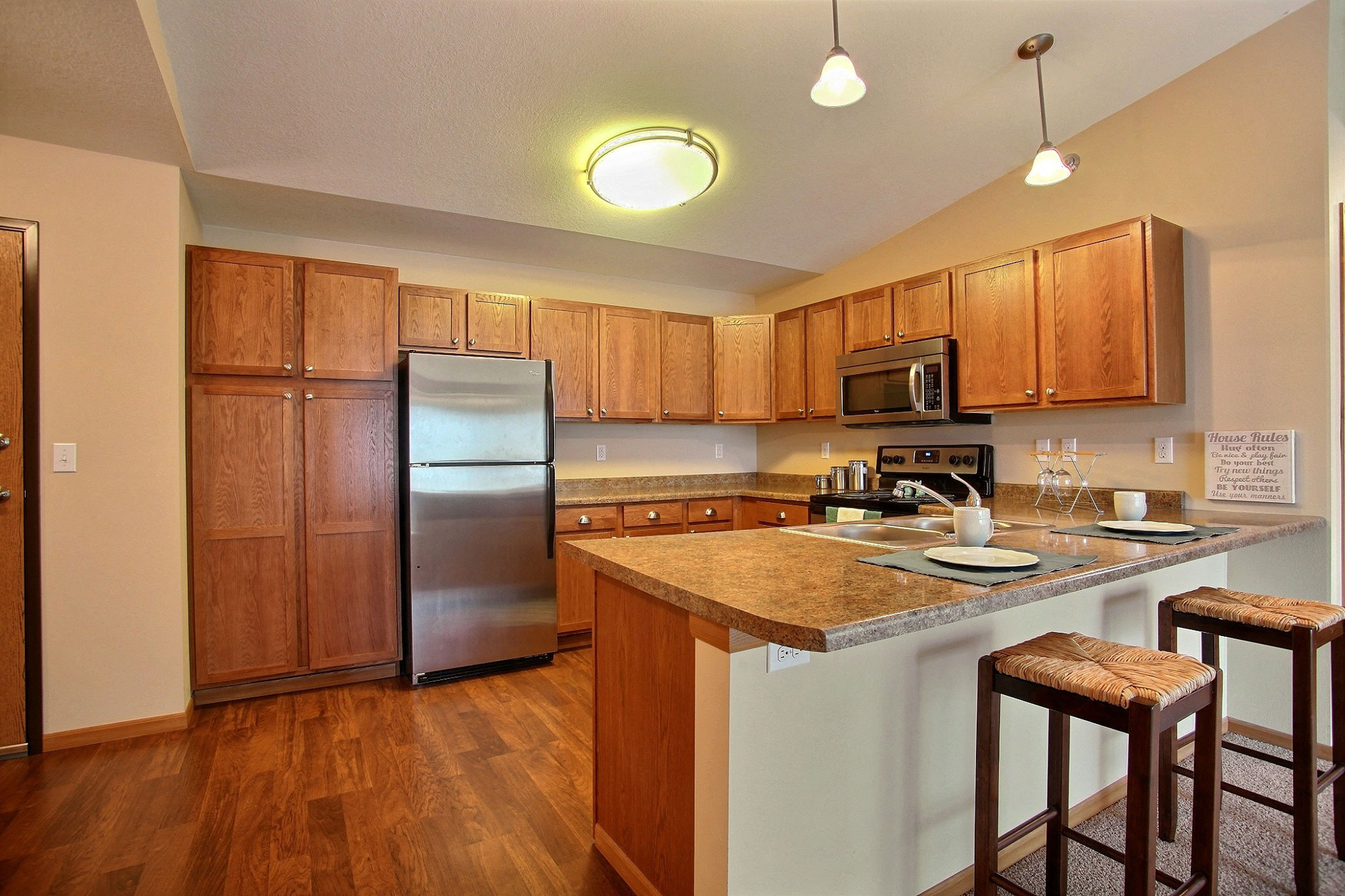 a kitchen with stainless steel appliances and wooden cabinets. Fargo, ND Wolf Creek Apartments
