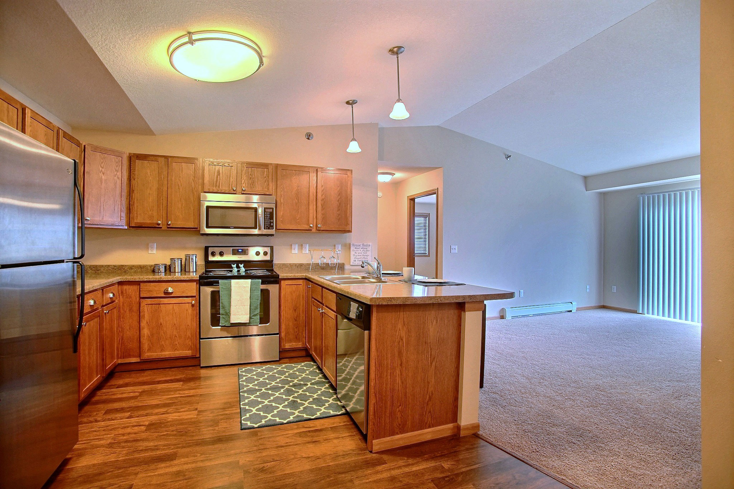 a kitchen with stainless steel appliances and wooden cabinets. Fargo, ND Wolf Creek Apartments