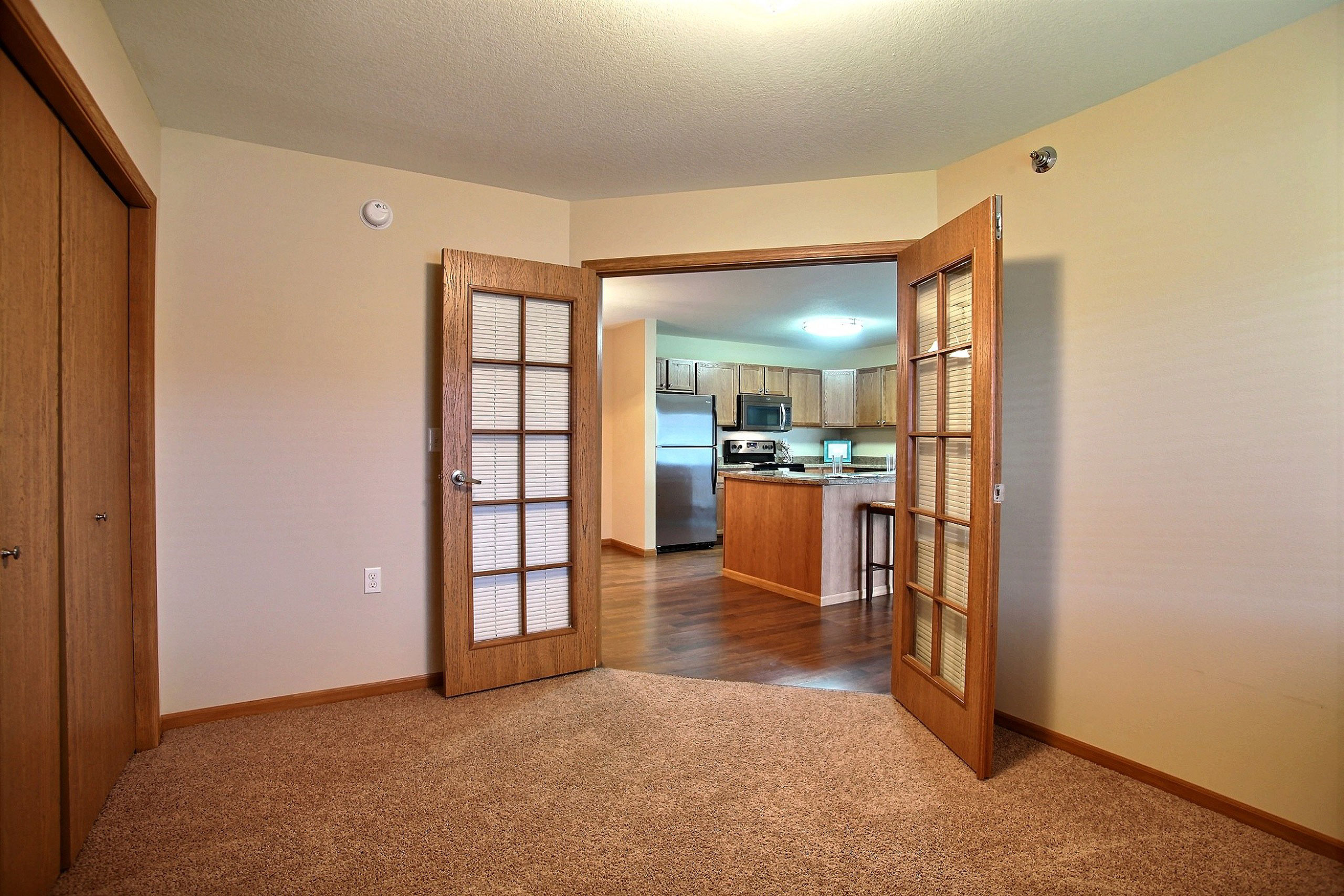 a bedroom with a closet and a door to a kitchen. Fargo, ND Wolf Creek Apartments