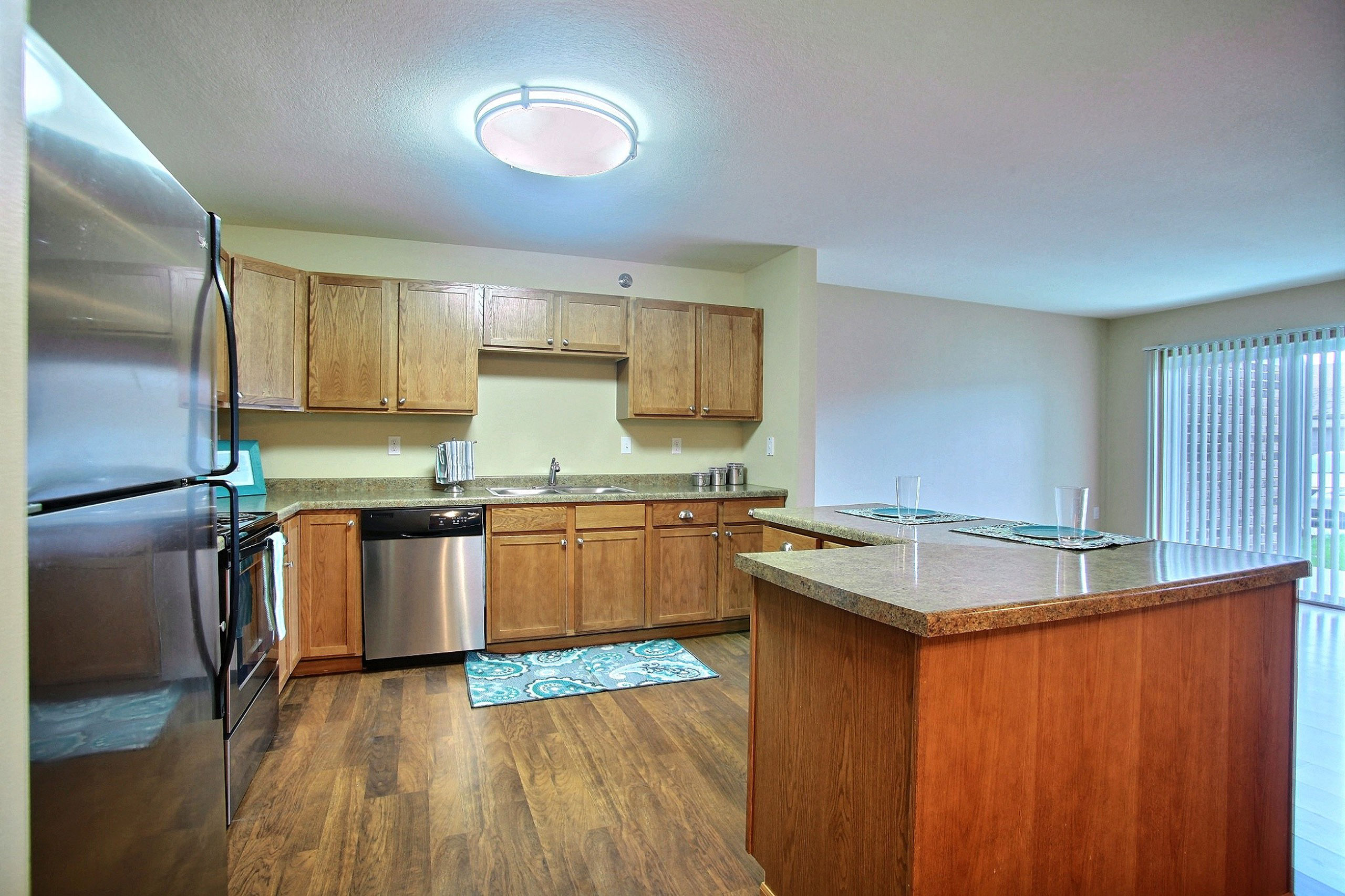 a kitchen with stainless steel appliances and wooden cabinets. Fargo, ND Wolf Creek Apartments