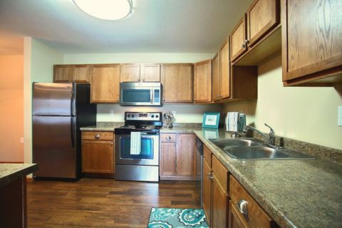 a kitchen with stainless steel appliances and wooden cabinets. Fargo, ND Wolf Creek Apartments