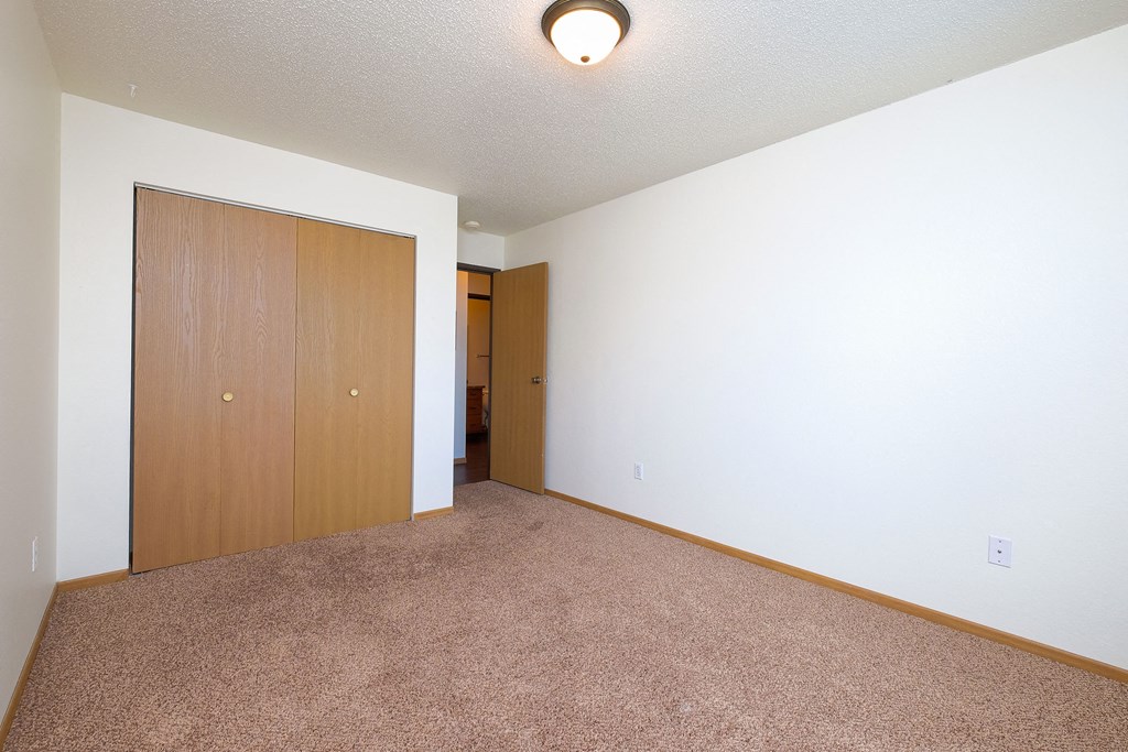a bedroom with a closet and a door to a hallway. Moorhead, MN Woodstone Apartments