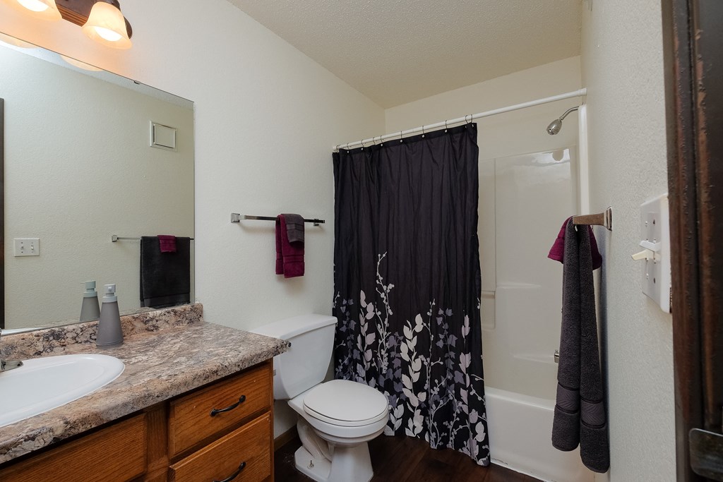 a bathroom with a shower toilet and sink. Moorhead, MN Woodstone Apartments