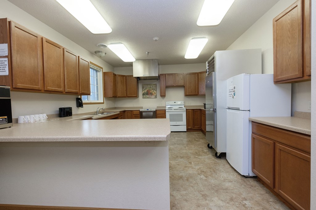 a kitchen with white appliances and wooden cabinets .Fargo, ND North Sky Apartments