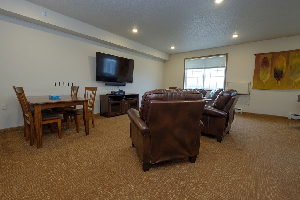 a community room with chairs and a tv. Fargo, ND North Sky Apartments