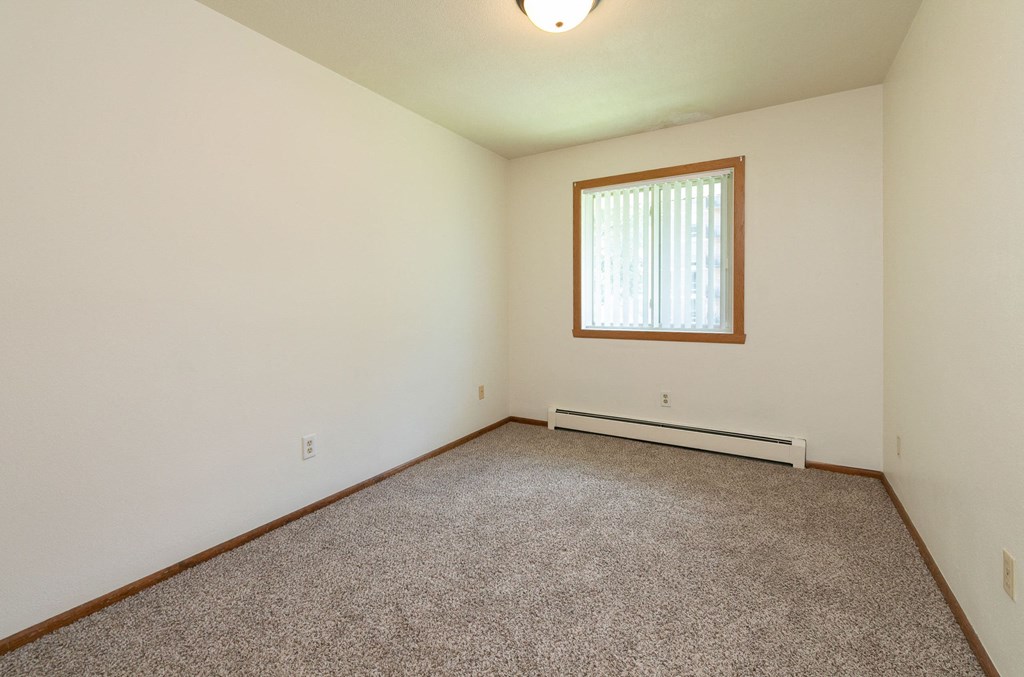 a bedroom with carpet and a window. Fargo, ND Islander Apartments