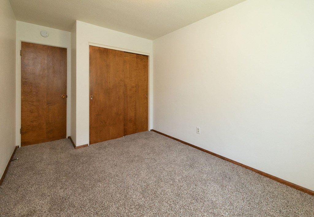 a bedroom with a closet and a door to a hallway. Fargo, ND Islander Apartments
