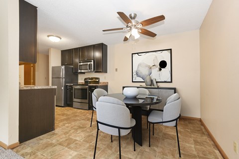 a dining area with a table and chairs and a kitchen with stainless steel appliances