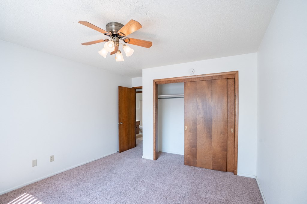 a bedroom with a ceiling fan and a closet. Fargo, ND Betty Ann Apartments