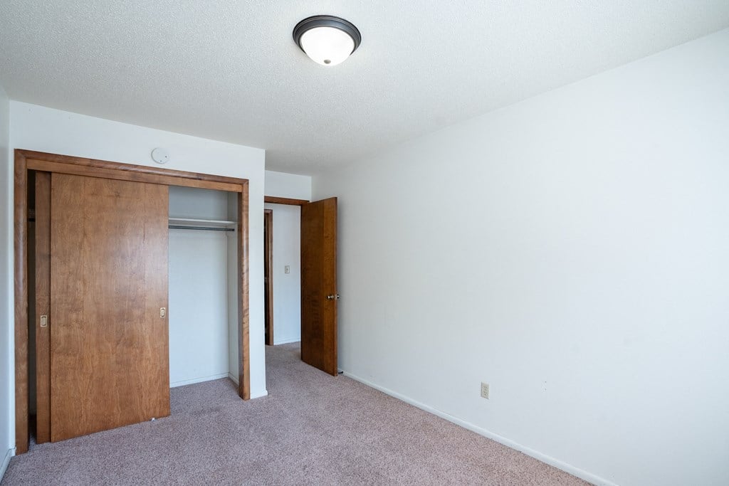 an empty room with a closet and a door to a bedroom. Fargo, ND Betty Ann Apartments