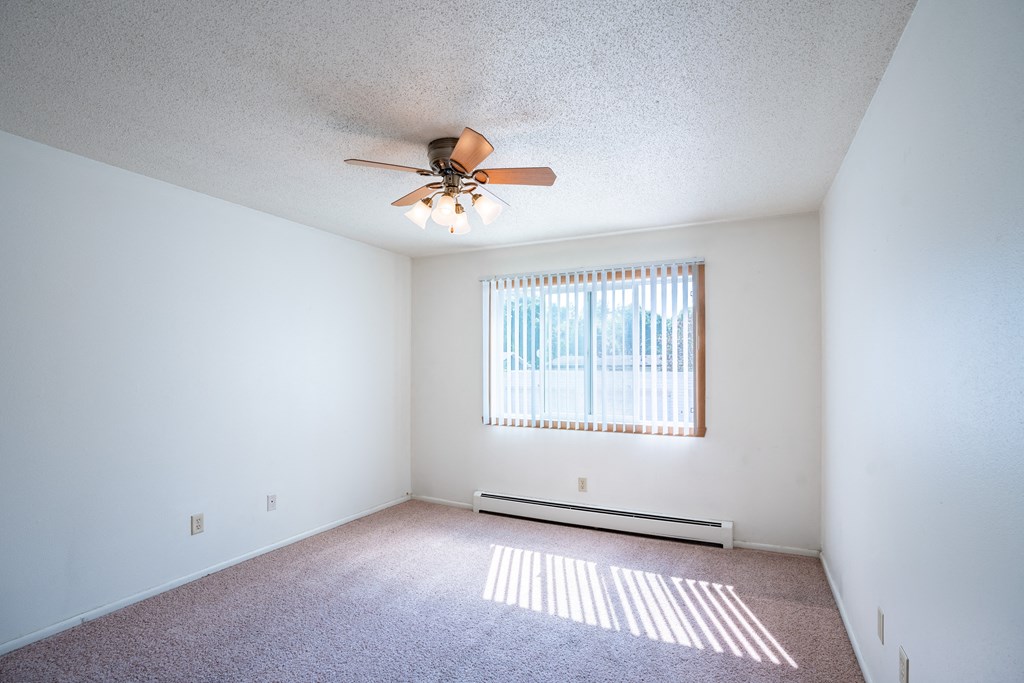 a bedroom with a ceiling fan and a window. Fargo, ND Betty Ann Apartments