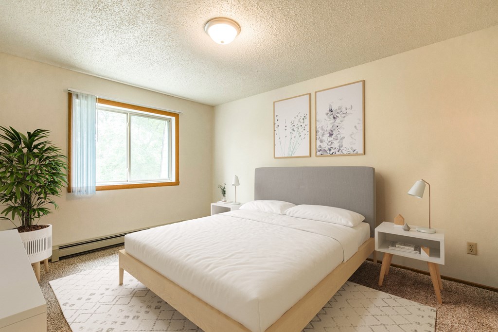 Bismarck, ND Brandon Apartments | Bedroom Bismarck, ND Brandon Apartments. The room showcases a comfortable bed with neatly arranged bedding and a calm ambiance. Soft lighting adds to the peaceful atmosphere, while a window allows natural light to fill the space. It's a tranquil retreat for rest and relaxation.