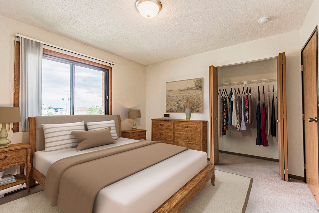 Bismarck, ND Eagle Sky I. A bedroom with a bed and a wardrobe. Bright natural light fills the room from a large window at the head of the bed.