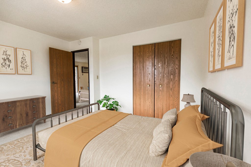 Bismarck, ND Eagle Sky I Apartments | Bedroom Bismarck, ND Eagle Sky I. A bedroom with a bed and a wardrobe. The yellow accents on the bed make for a bright energetic room.