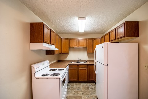 a kitchen with white appliances and wooden cabinets and a refrigerator