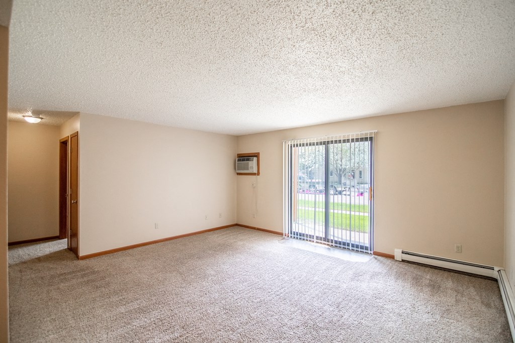 Bismarck, ND Eastbrook Apartments. A spacious living room with a sliding glass door leading to a yard