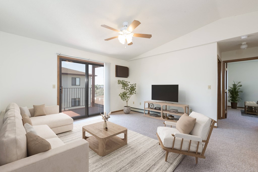Bismarck, ND Fairview a living room with white walls and a sliding glass door to a balcony. The furniture is a bright white such as the couch and chair.