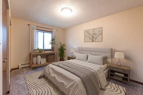 a bedroom with a bed and window. Bismarck, ND Newgate Apartments