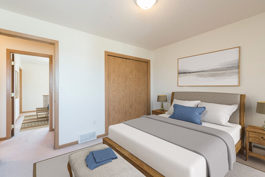 Bismarck Pebble Creek Apartments bedroom. The room features modern furnishings, soft lighting, and a comfortable bed. Theres a closet in the corner of the room for storage or clothing.