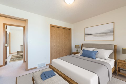 Bismarck Pebble Creek Apartments bedroom. The room features modern furnishings, soft lighting, and a comfortable bed. Theres a closet in the corner of the room for storage or clothing.