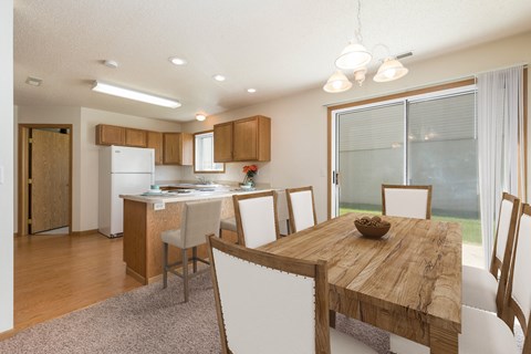 a dining room and kitchen with a wooden table and chairs