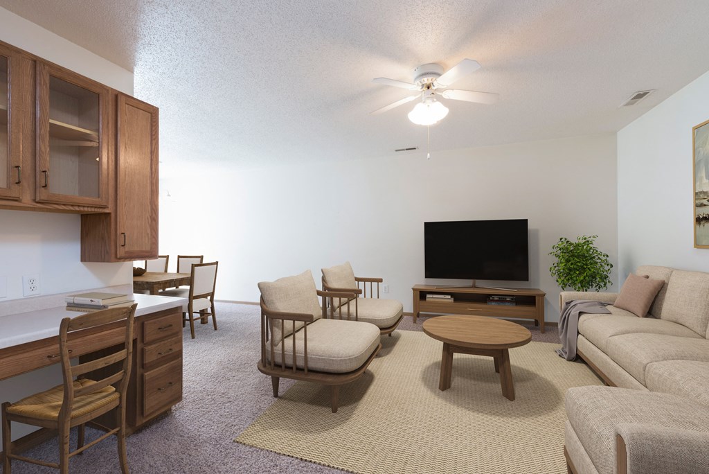 Bismarck Pebble Creek Apartments. The spacious living room is tastefully decorated with stylish furniture, ample natural light, and a cozy atmosphere. Theres overhead lighting with a touch of natural light from the dining room.