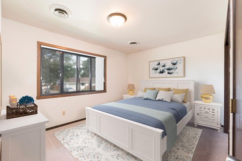 Bismarck, ND Riverpark Apartments  a bedroom with a large window and a large bed with blue bedding