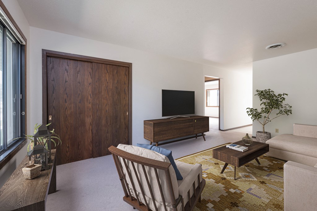 Bismarck, ND Riverpark Apartments | Living Bismarck, ND Riverpark Apartments The room features large windows that offer scenic views of the surrounding area, comfortable seating, and modern decor. The room has a closet near the door for convenience to store outdoor clothing