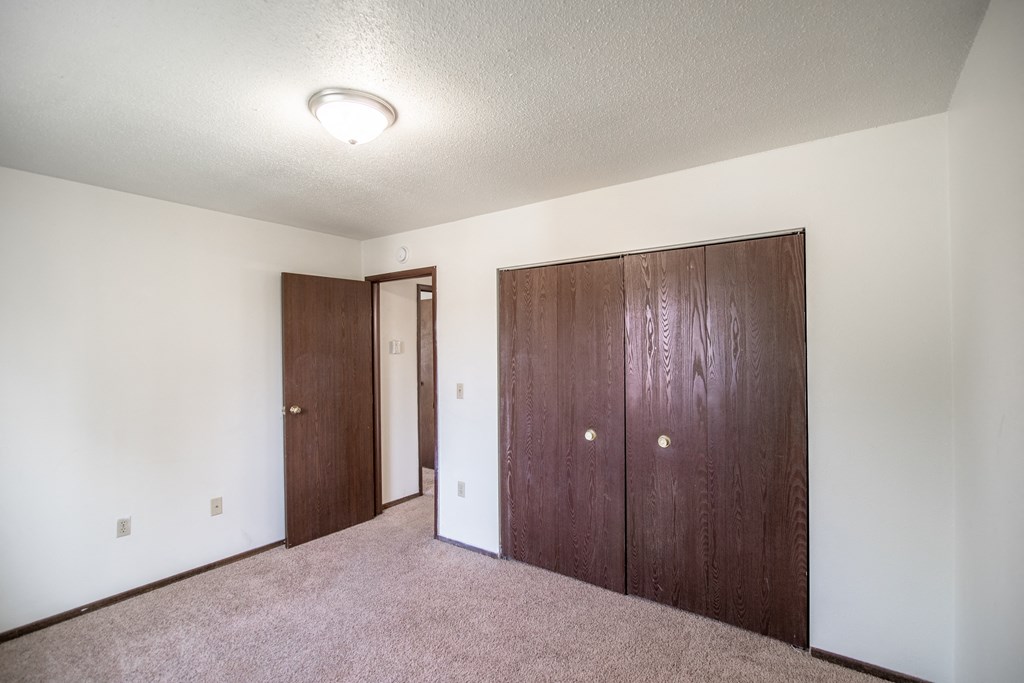 Bismarck, ND Rosser Apartments. a bedroom with two doors and a carpeted floor