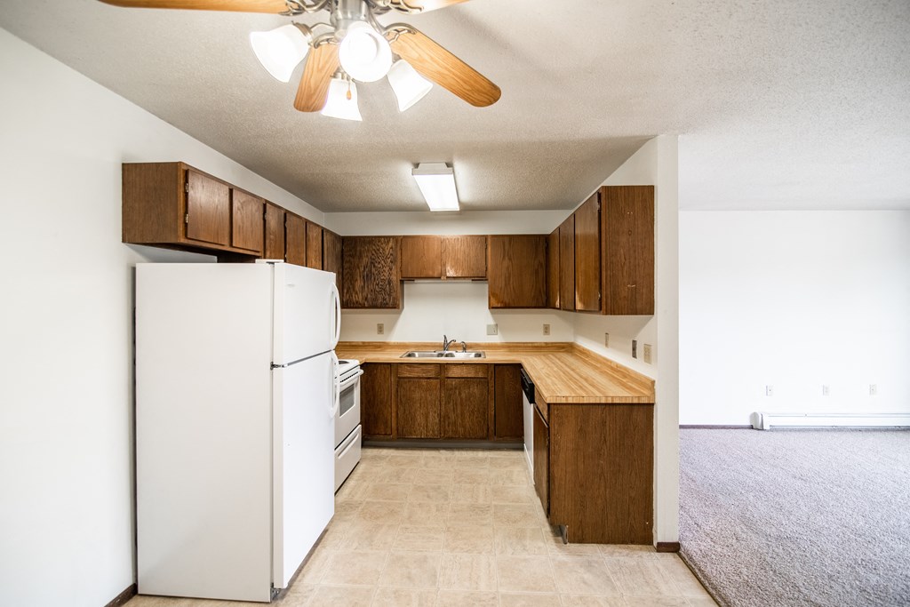 Bismarck, ND Rosser Apartments. a kitchen with a white refrigerator freezer next to a stove top oven