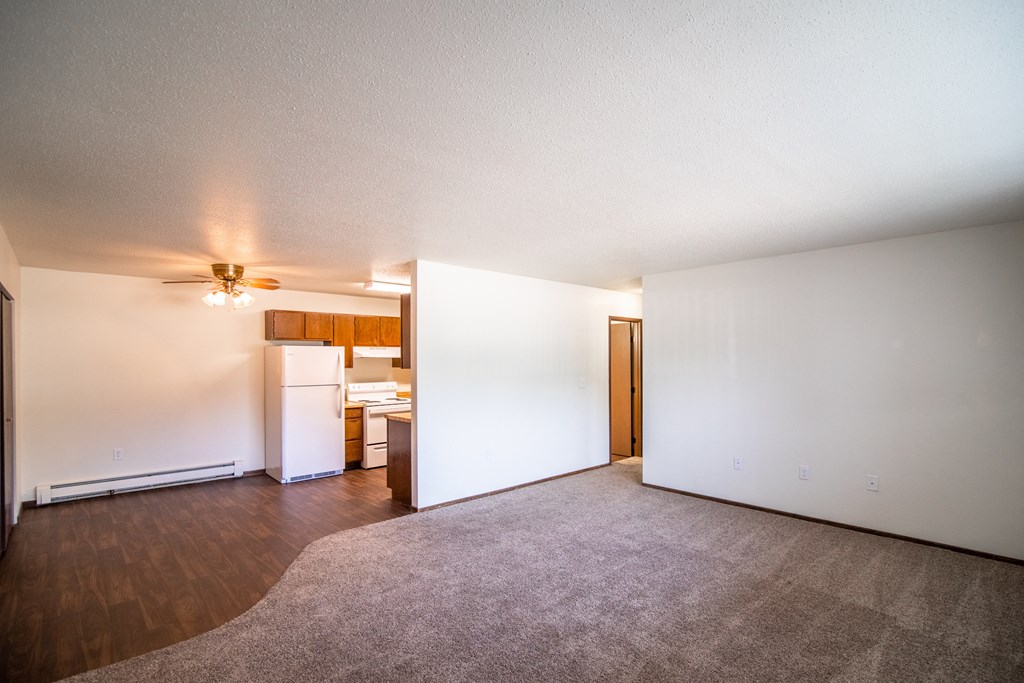 Bismarck, ND Rosser Apartments. an empty living room with a kitchen in the background