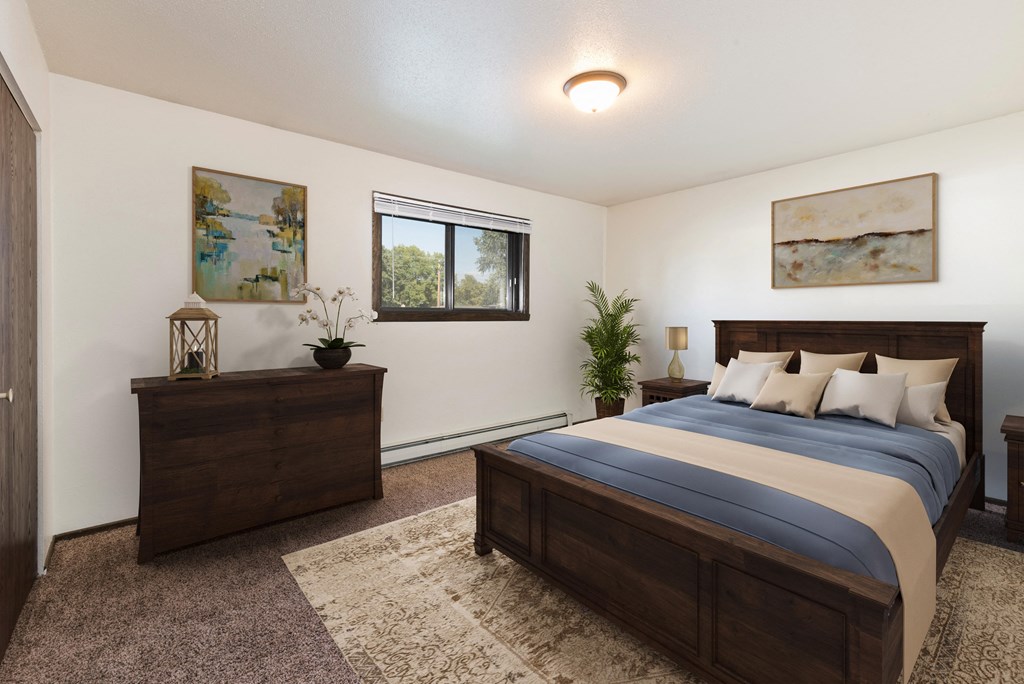 Bismarck, ND Rosser Apartments. A bedroom with dark wood bed, dresser, and night stands. A small window fills the room with natural light