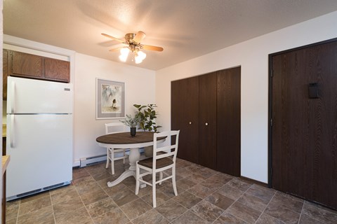 Bismarck, ND Rosser Apartments. A dining room with a table and two chairs. The overhead fan and light brighten the room. The entrance to the unit is next to a large closet for shoes and coats to be hung up.
