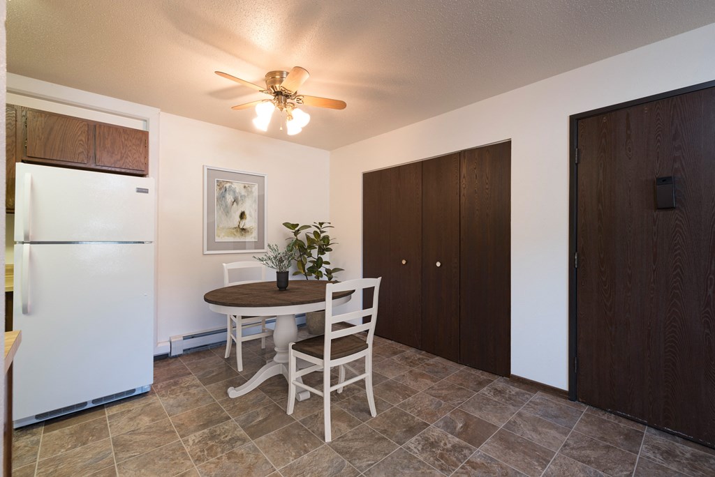 Bismarck, ND Rosser Apartments. A dining room with a table and two chairs. The overhead fan and light brighten the room. The entrance to the unit is next to a large closet for shoes and coats to be hung up.
