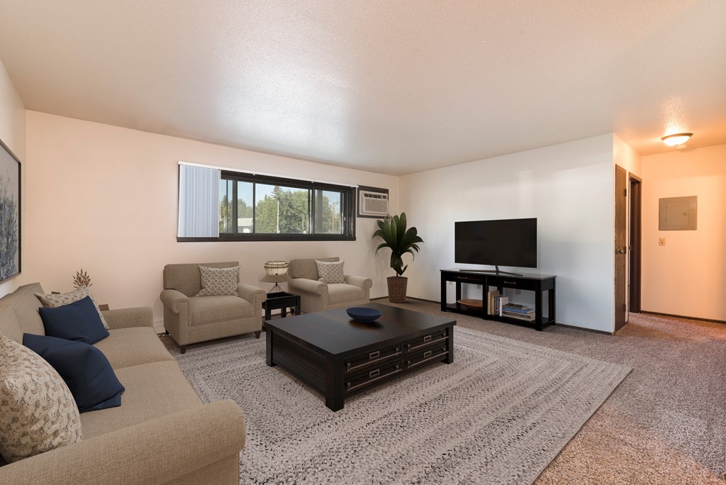 Bismarck, ND Rosser Apartments. A living room with couches, a coffee table, and a tv. A long window fills the room with bright natural light
