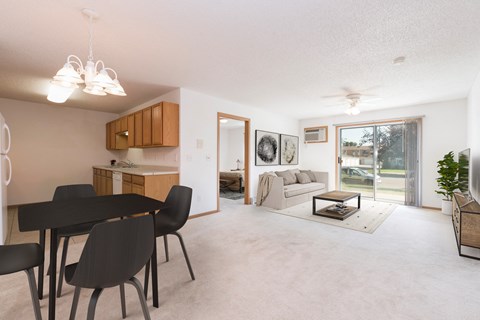 Sierra Ridge Apartments in Bismarck, ND | The space features an open floor plan with comfortable seating, a well-appointed dining table, and tasteful decor. The sliding glass door brightens the room w