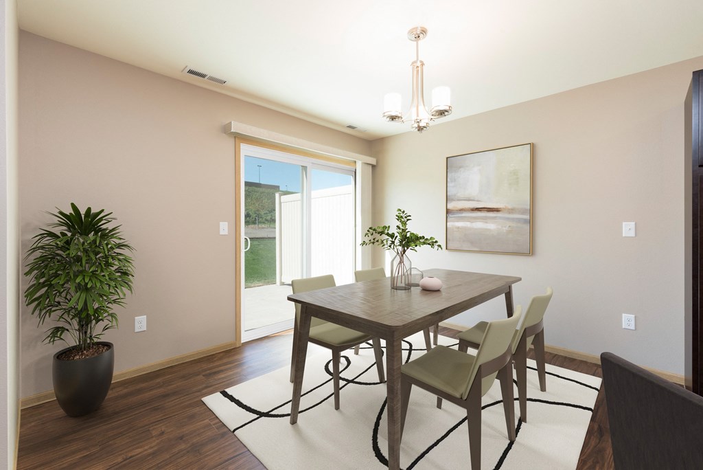Bismarck, ND Stonefield Townhomes | Dining Room Bismarck, ND Stonefield Townhomes. The space features a well-appointed dining table with 4 chairs, modern kitchen appliances, and tasteful decor. Bright natural light fills the room from the glass sliding door.