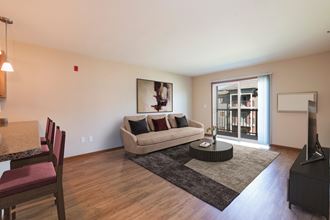 Bismarck, ND Stonefield Apartments. A living room with a sliding glass door leading to a balcony