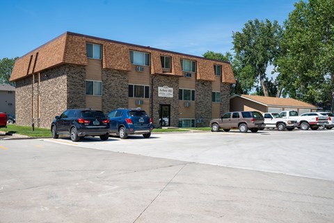 A parking lot in front of a building with cars parked. Bismarck, ND Arbor 406 Apartments