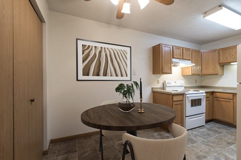 a kitchen and dining room with a table and chairs and a painting on the wall. Bismarck, ND Belmont East Apartments