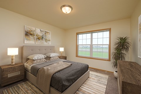 A bedroom with a large bed and a window. West Fargo, ND Charleswood Townhomes.