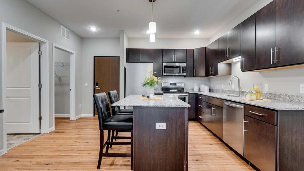 a kitchen with a island and a table with chairs. Circle Pines, MN Lexington Lofts