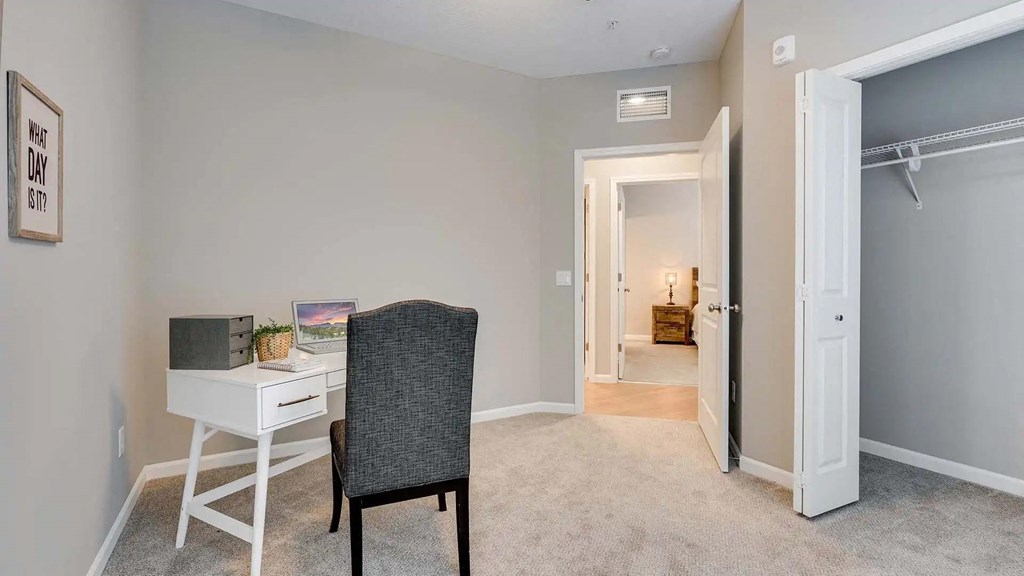 a bedroom with a desk with a chair and a door to a bathroom.  Circle Pines, MN Lexington Lofts
