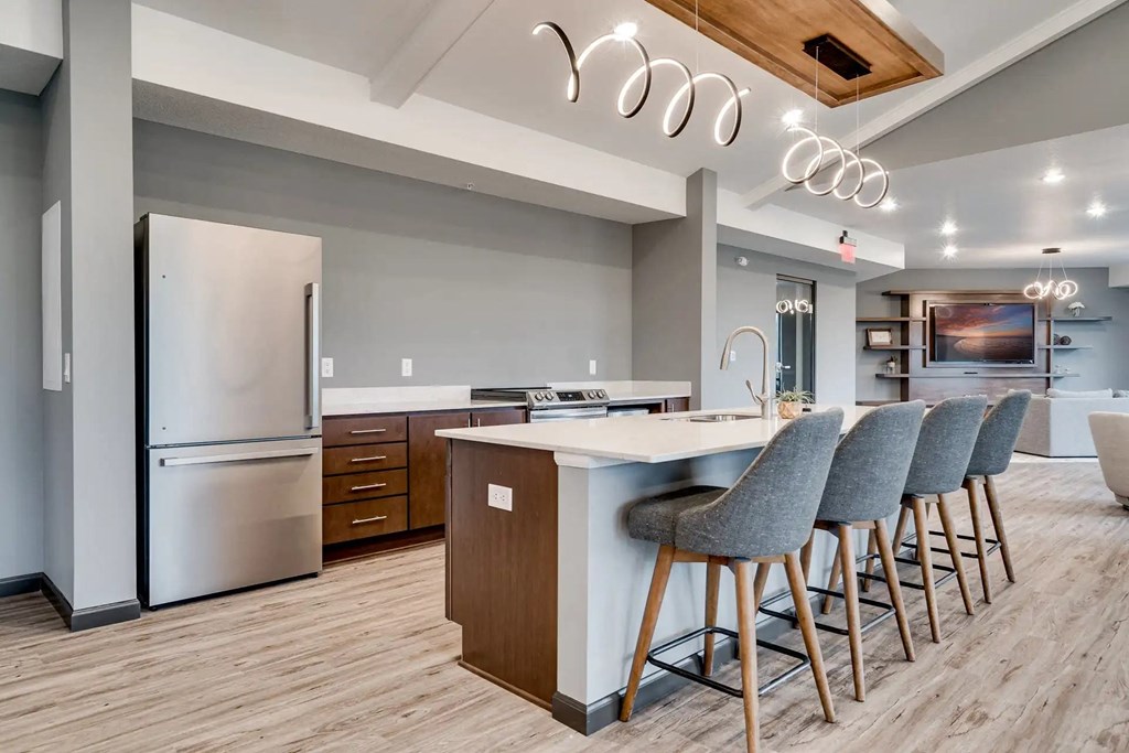 a kitchen with a island and chairs in front of a refrigerator. Circle Pines, MN Lexington Lofts