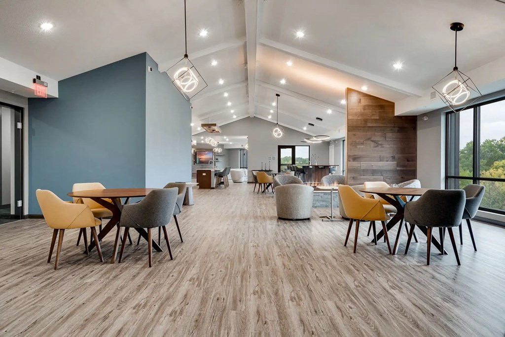 a dining room with tables and chairs and a large window. Circle Pines, MN Lexington Lofts