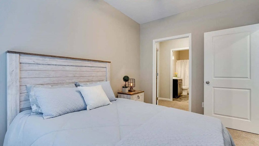 a bedroom with a bed and a door to a bathroom. Circle Pines, MN Lexington Lofts