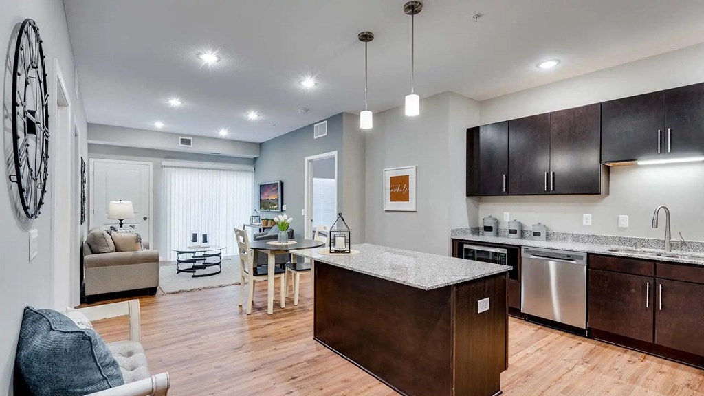 a kitchen with an island and a living room with a couch. Circle Pines, MN Lexington Lofts