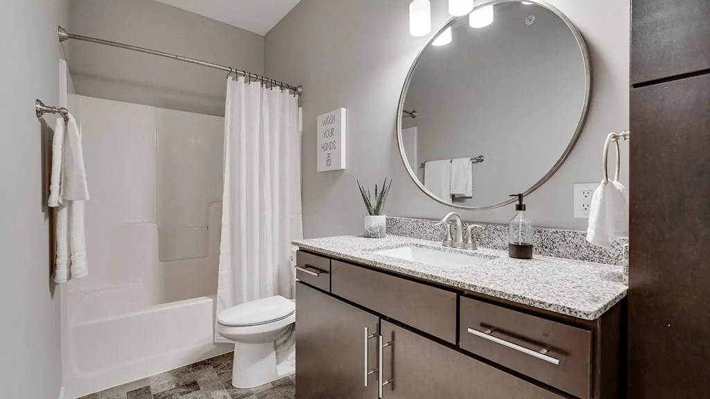 a bathroom with a sink and a toilet and a mirror. Circle Pines, MN Lexington Lofts